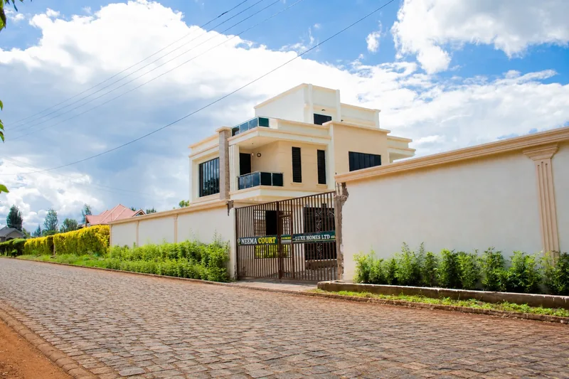 Neema Court maisonette seen from the cobbled access road, with gate, perimeter wall and landscaping