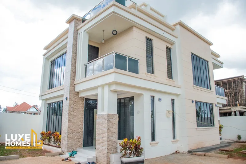 Front elevation of a Neema Court maisonette with balcony, potted plants and paved compound
